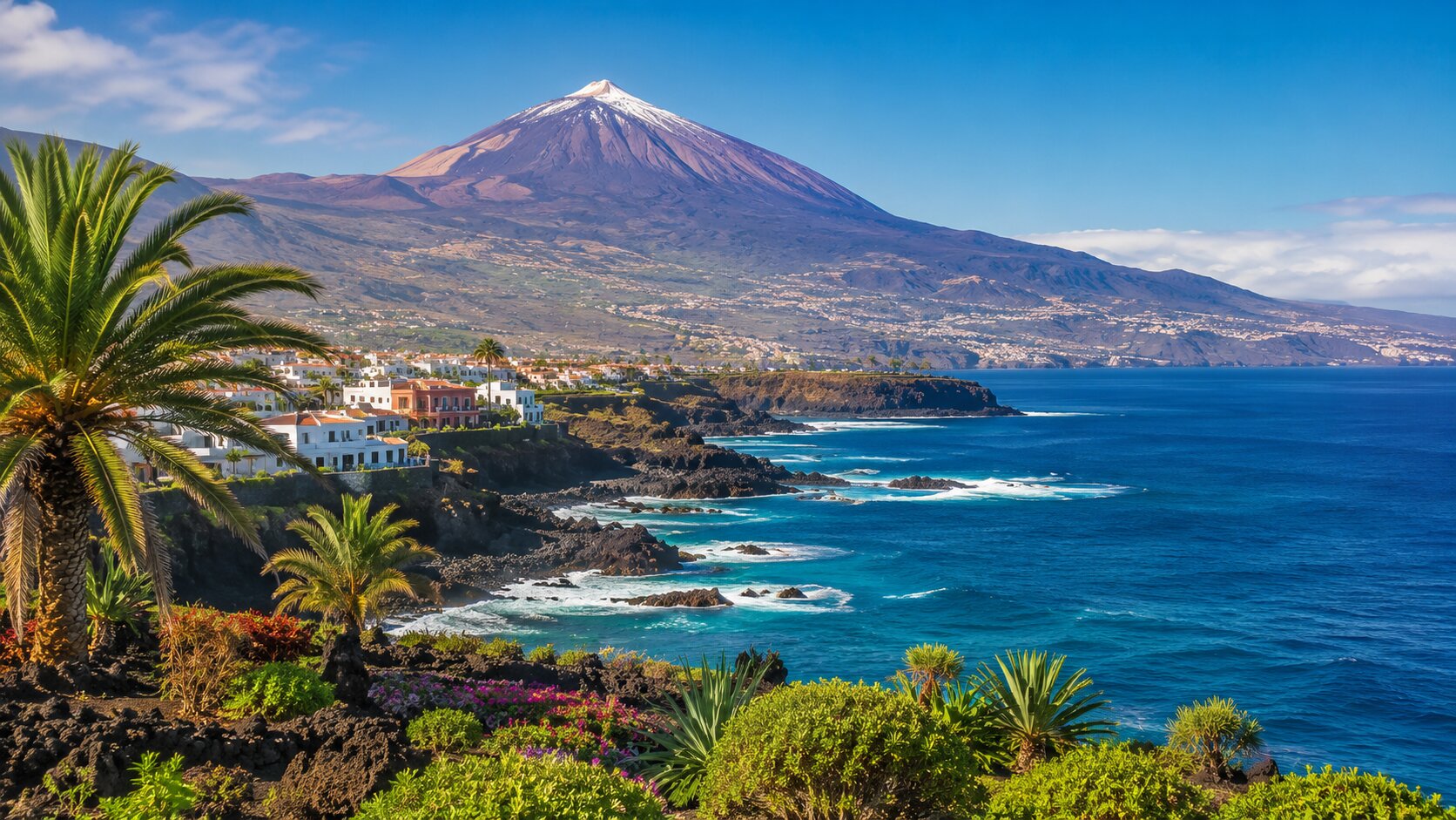 Küste von Teneriffa mit Palmen und schneebedecktem Teide im Hintergrund