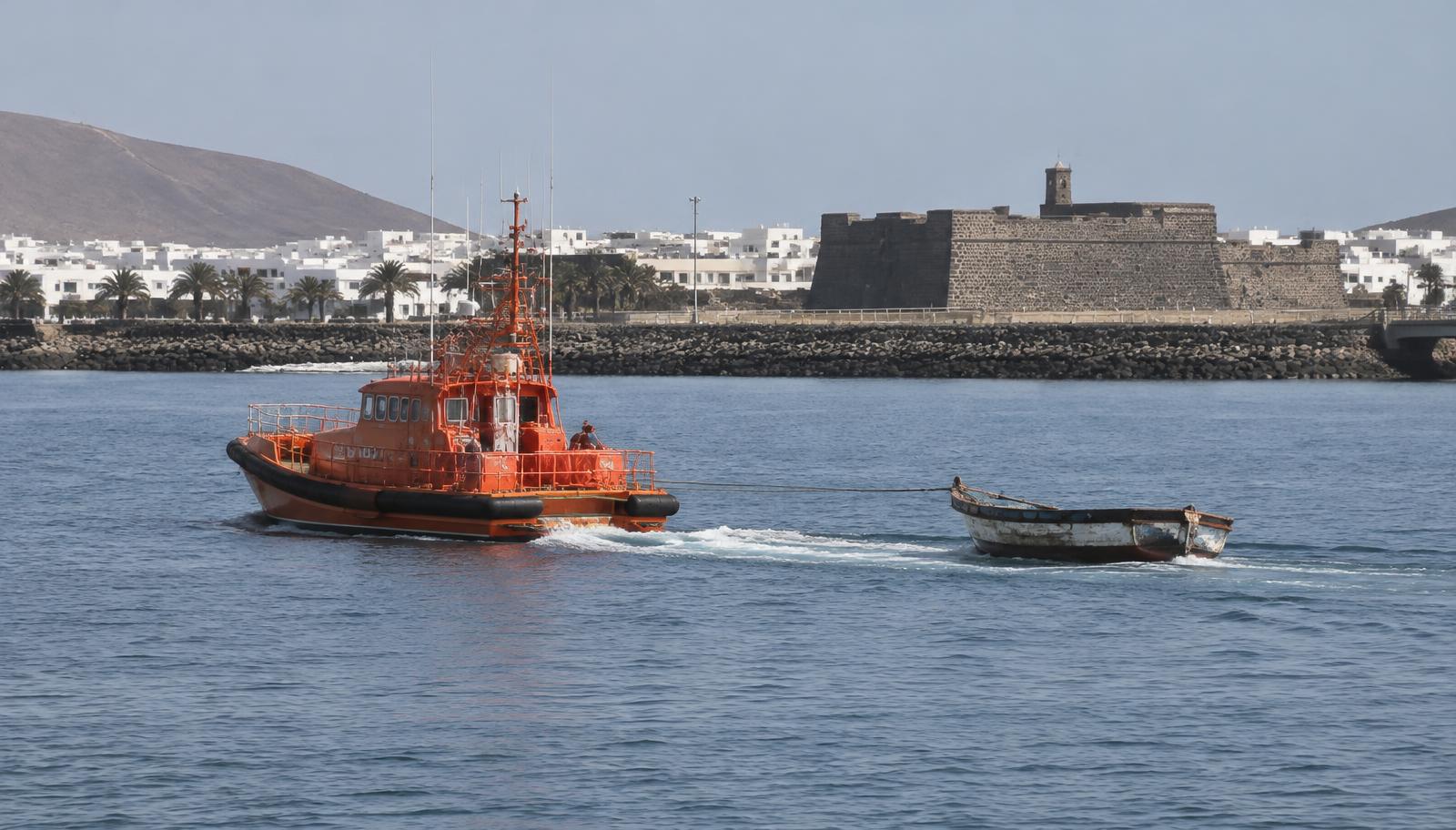 Rettungsboot schleppt kleines Holzboot in den Hafen von Arrecife