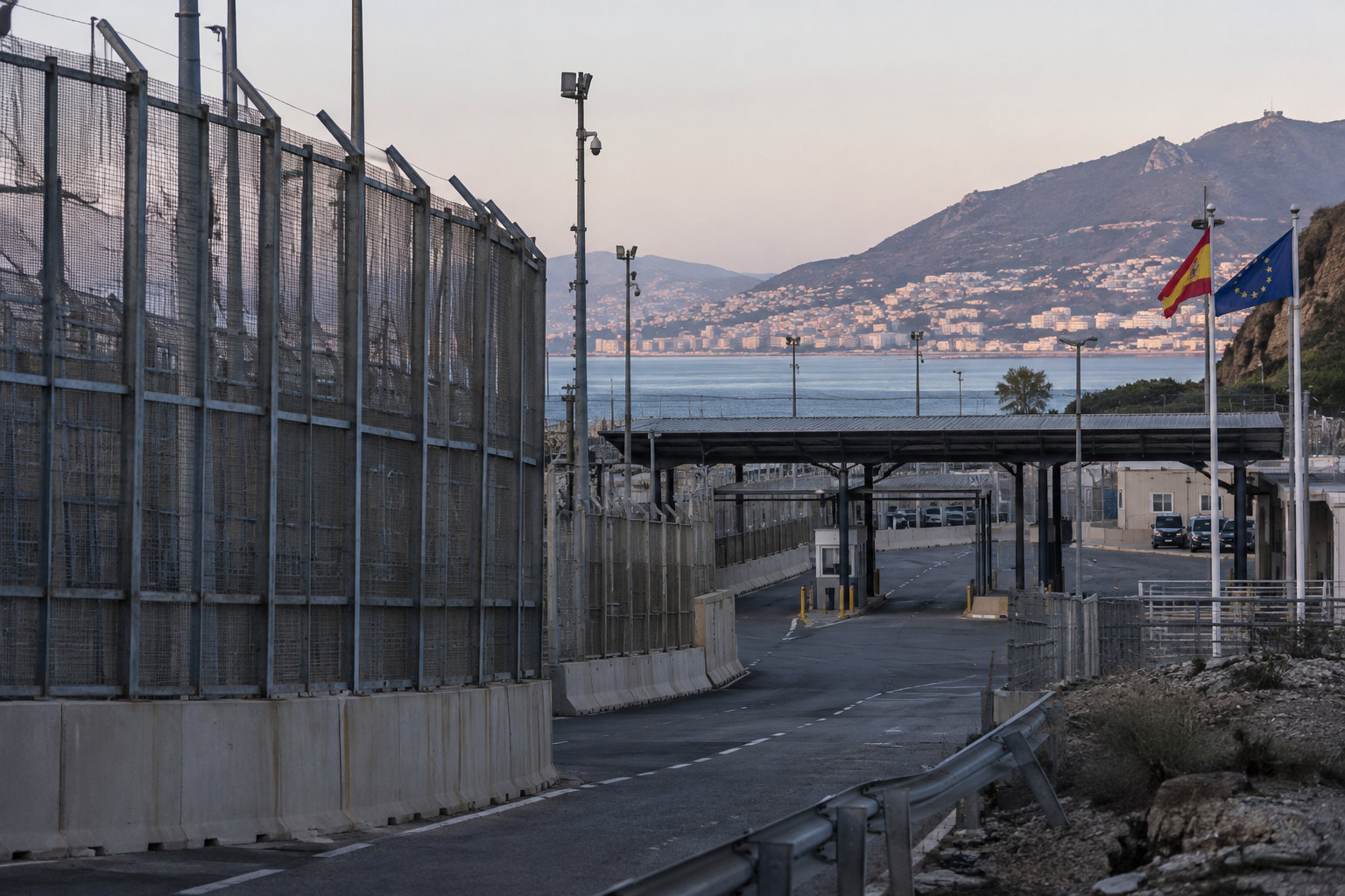 Grenzzaun und EU-Flaggen an einem Kontrollpunkt in Ceuta als Symbol der europäischen Migrationspolitik