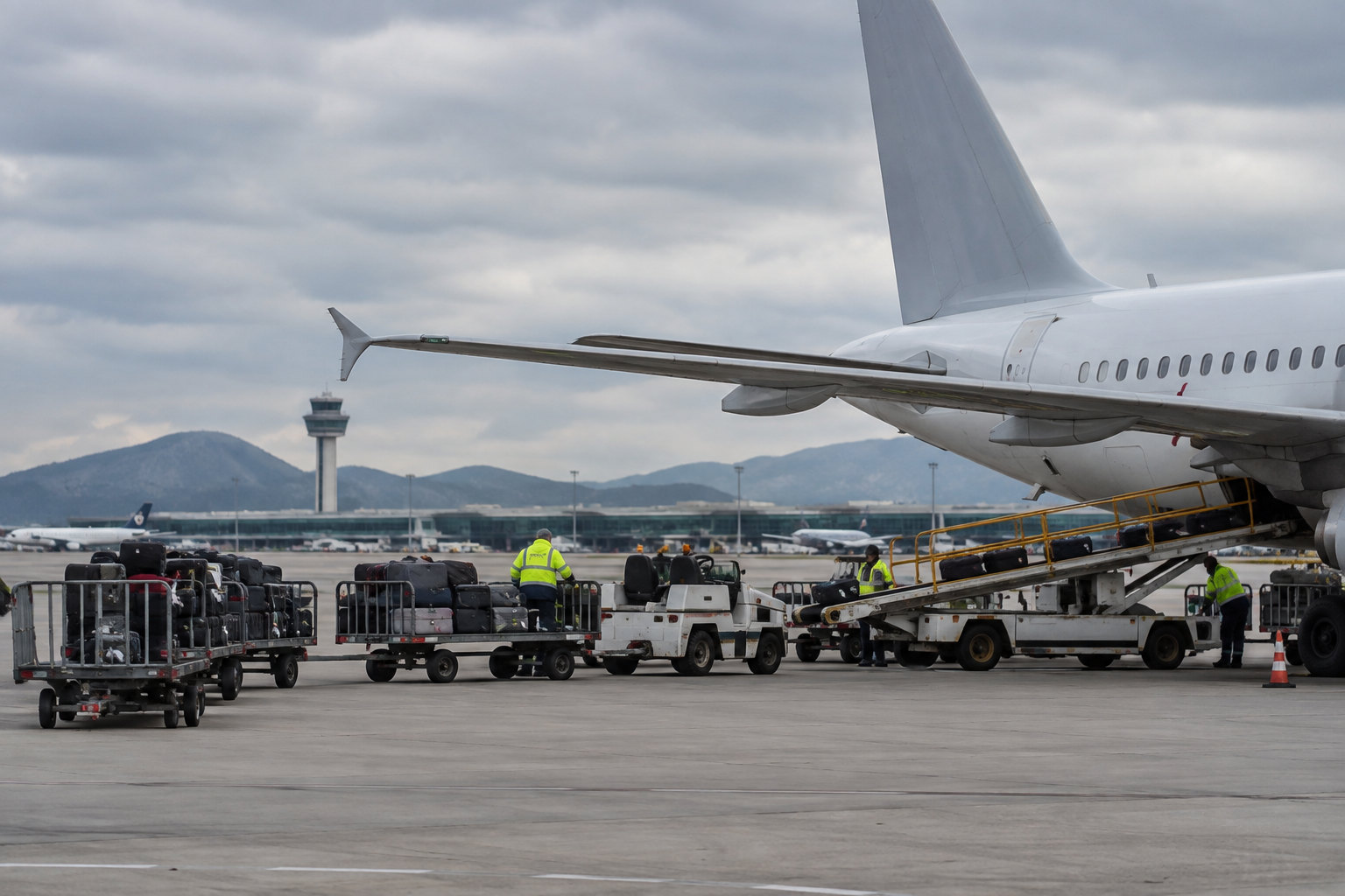 Bodenabfertigung mit Gepäckwagen und Flugzeugen am Flughafen Barcelona-El Prat