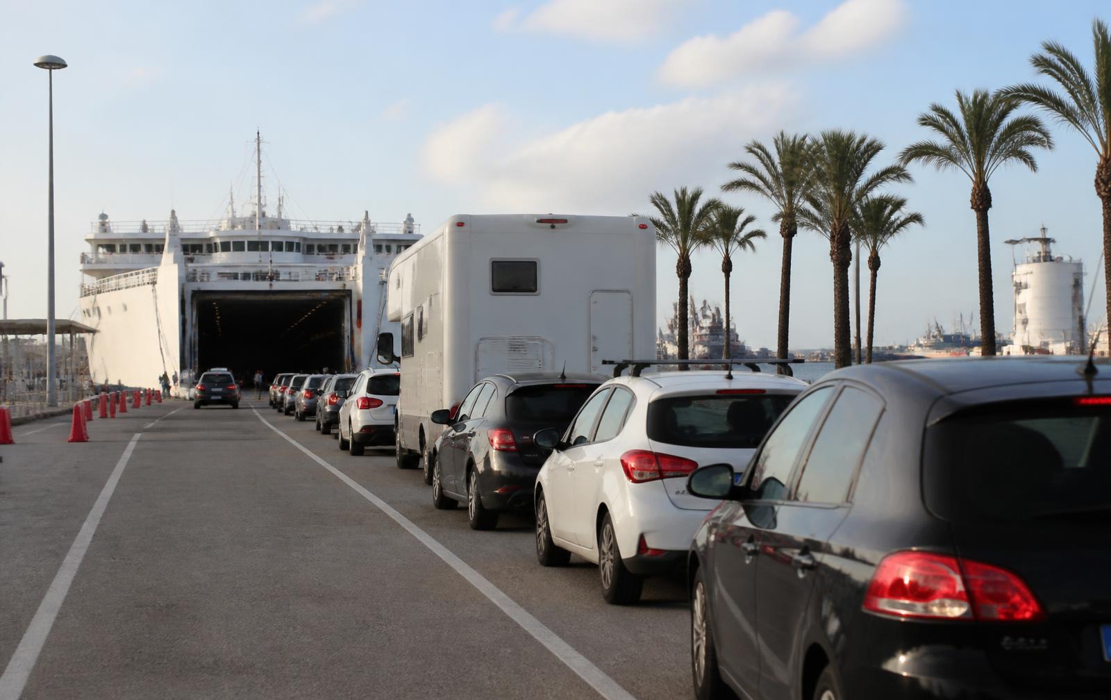 Autos und ein Wohnmobil warten an einem Fährhafen auf den Balearen